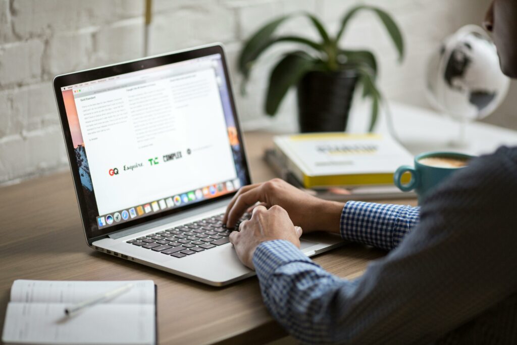 pexels-photo-374074-374074-1 A man working on a laptop at a desk with coffee, showcasing remote work in a modern office setting.