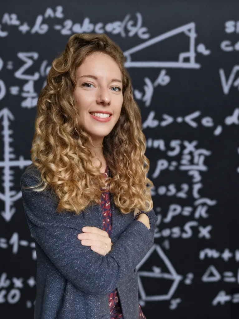 photo-767x1024 Enseignante souriante posant devant un tableau rempli de formules mathématiques